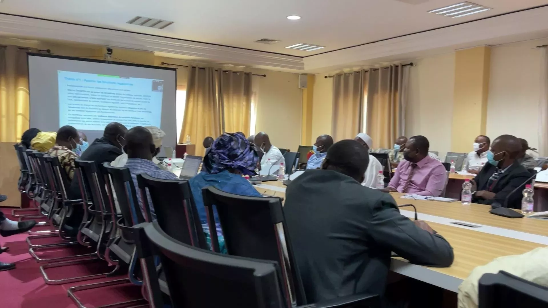 People seated at a conference table in a meeting room in Panama, focusing on a presentation being displayed on a screen at the front.