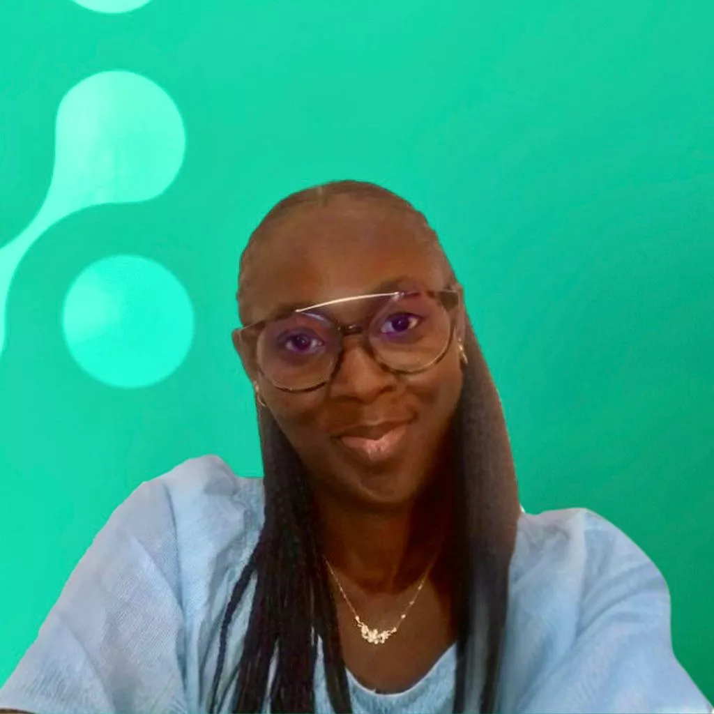 A person wearing glasses and a light blue top smiles in front of a teal background with circular patterns.